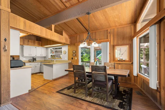 a dining room with wooden floor and large windows