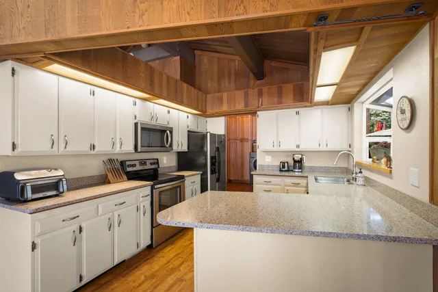 a kitchen with stainless steel appliances granite countertop a sink a stove and cabinets
