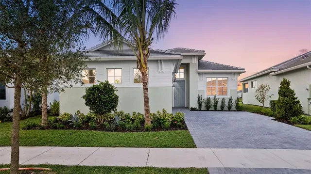 a front view of a house with a garden and trees