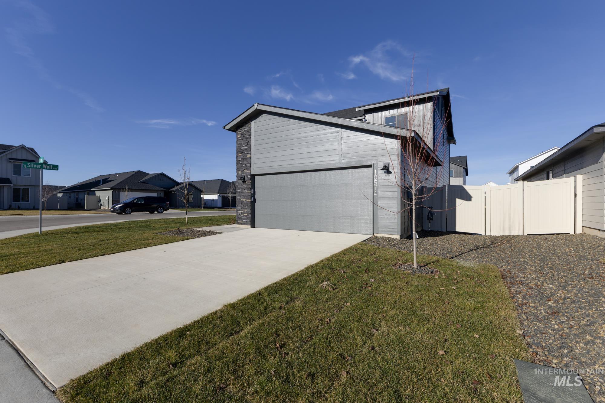 View of property exterior featuring concrete driveway, stone siding, and a residential view