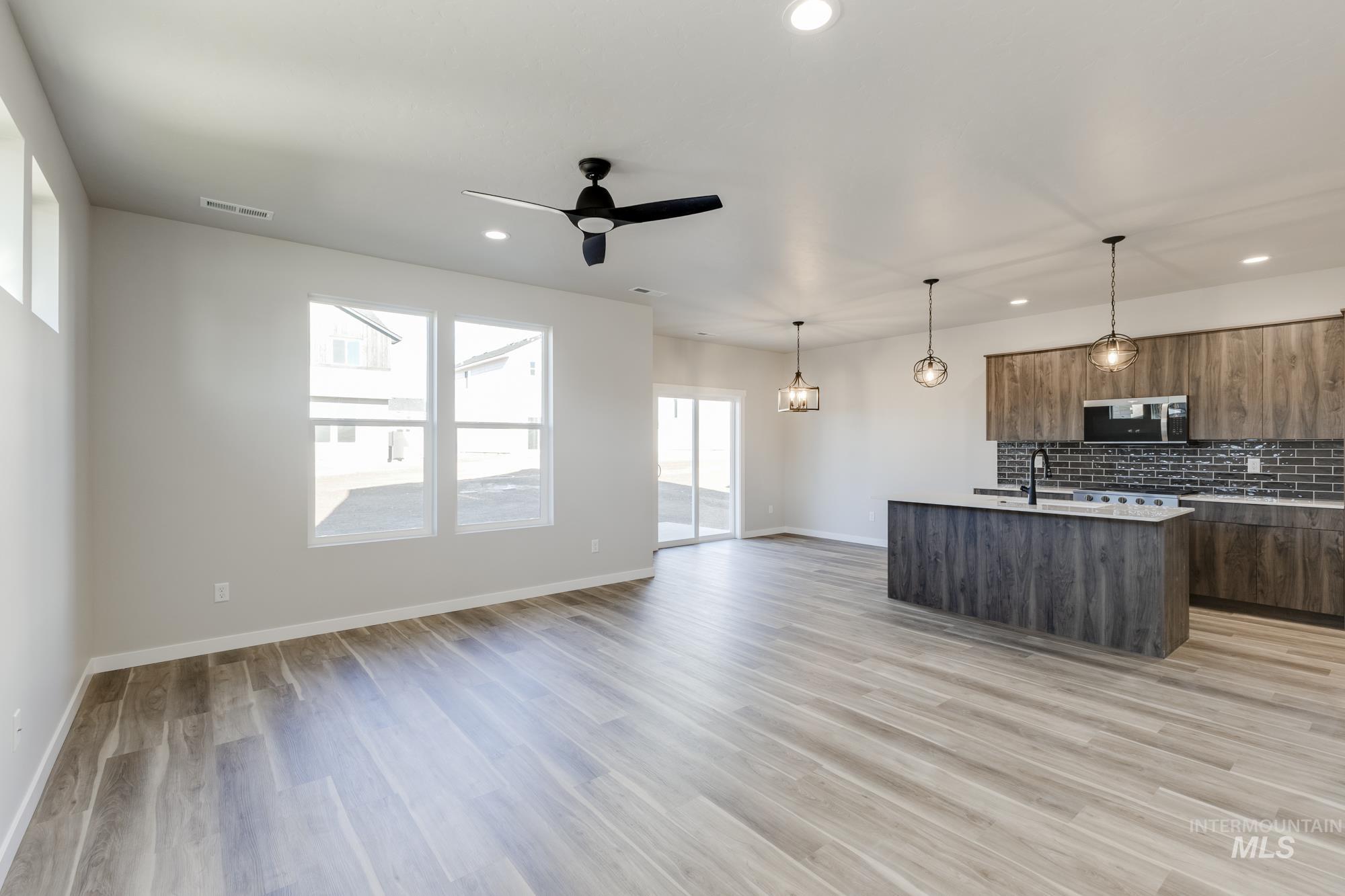 10574 West Teratai Street Star, ID 83669 - Photo 23 of 23 Kitchen with a center island with sink, modern cabinets, pendant lighting, open floor plan, and decorative backsplash