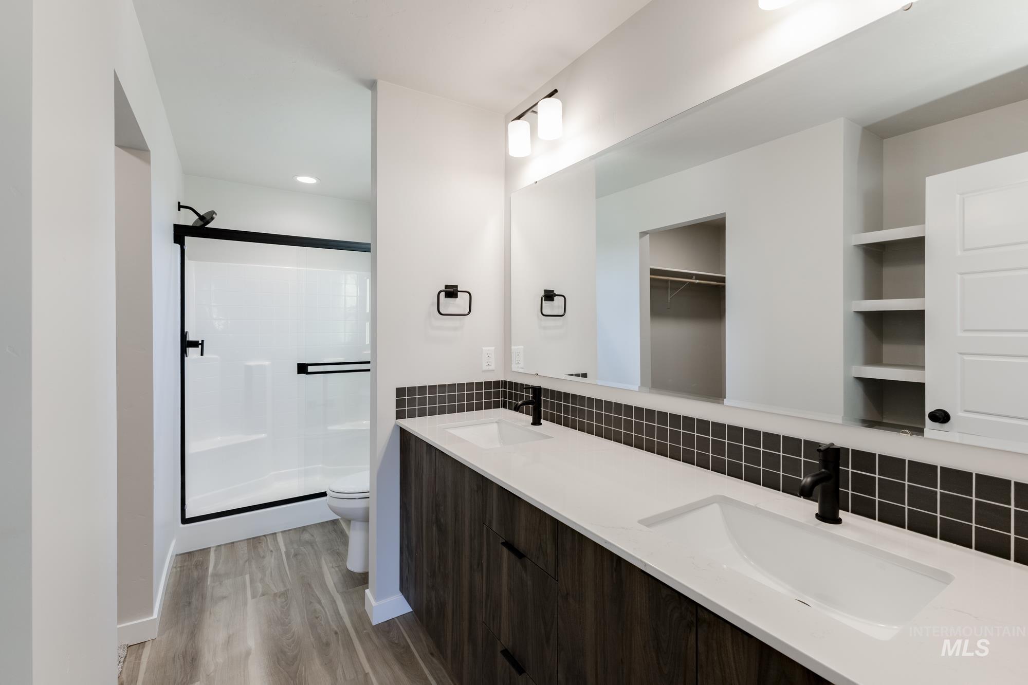 10574 West Teratai Street Star, ID 83669 - Photo 20 of 23 Full bath with a stall shower, double vanity, tasteful backsplash, light wood-style flooring, and a walk in closet