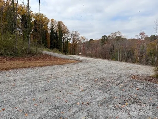 a view of dirt field with trees in the background
