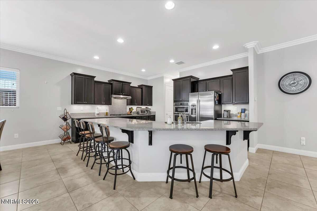1671 Crescent Pointe Court Reno, NV 89523 - Photo 14 of 44 a kitchen with stainless steel appliances a table chairs refrigerator and microwave