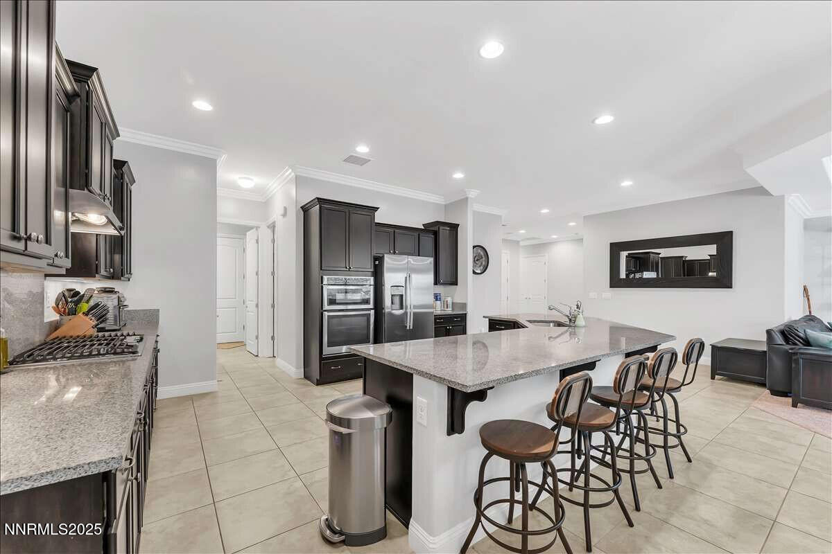 1671 Crescent Pointe Court Reno, NV 89523 - Photo 15 of 44 a kitchen with stainless steel appliances kitchen island granite countertop a refrigerator a stove a sink a dining table and chairs with wooden floor