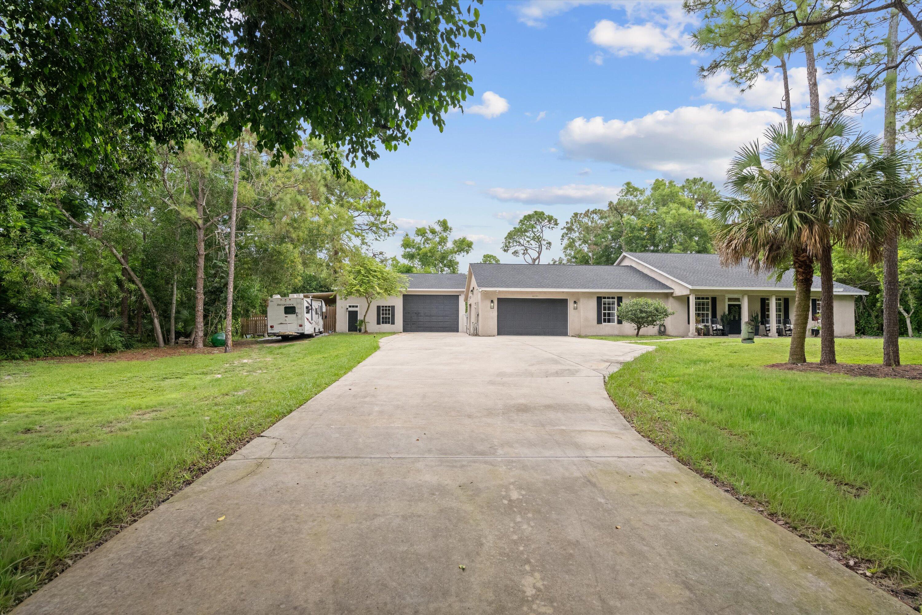 10771 154th Road North Jupiter, FL 33478 - Photo 3 of 87 a front view of a house with a yard and trees