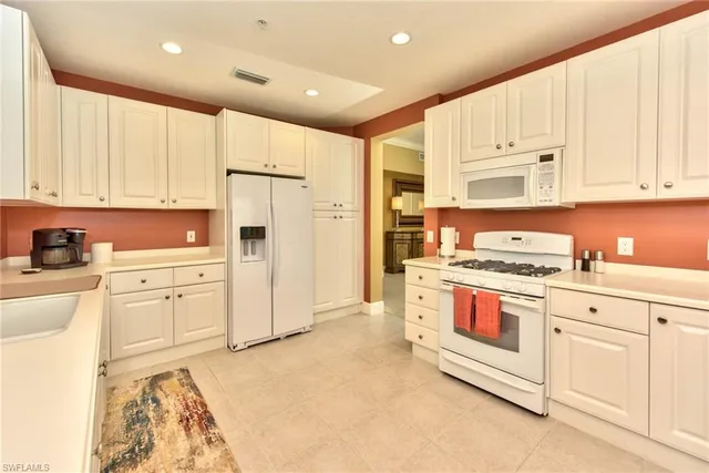 a kitchen with white cabinets and white appliances