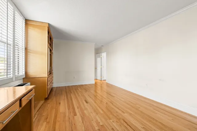 a view of an empty room with wooden floor and windows