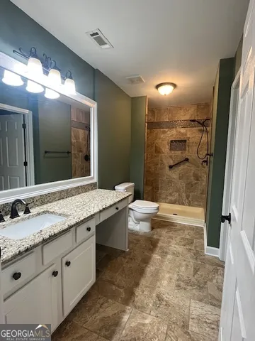 a bathroom with a granite countertop sink toilet and shower