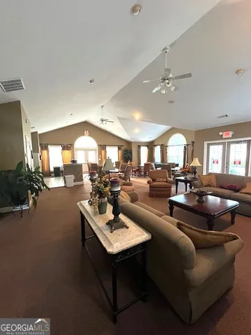 a living room with furniture kitchen view and a large window