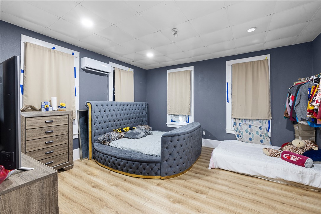 610 West Davis Street Hearne, TX 77859 - Photo 13 of 27 Bedroom featuring wood finished floors, a drop ceiling, and a wall unit AC