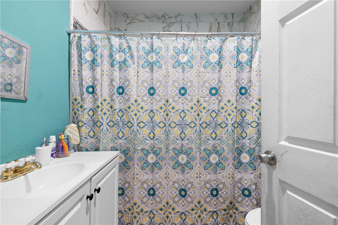 610 West Davis Street Hearne, TX 77859 - Photo 14 of 27 Full bath with vanity, a textured wall, and a shower with shower curtain