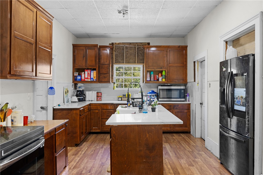 610 West Davis Street Hearne, TX 77859 - Photo 16 of 27 Kitchen with black fridge, open shelves, light wood-style floors, a center island, and a drop ceiling