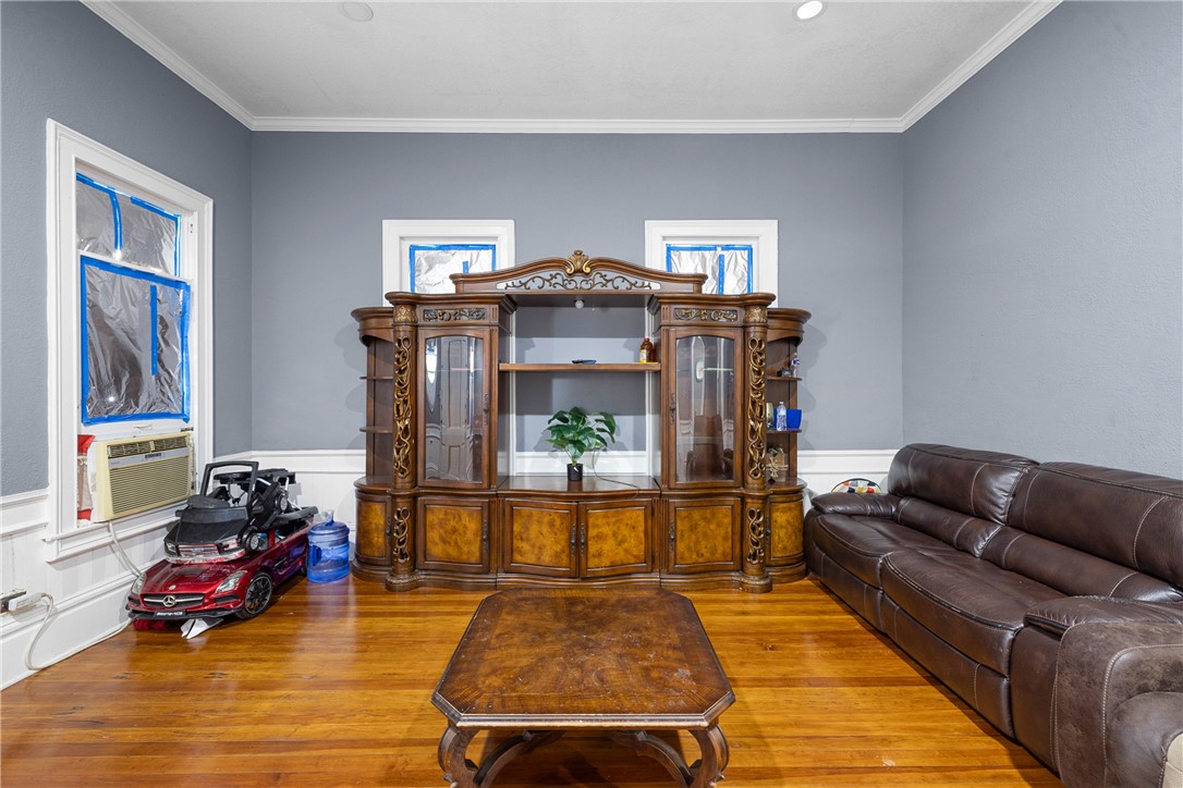 610 West Davis Street Hearne, TX 77859 - Photo 10 of 27 Living area with a wainscoted wall, ornamental molding, wood-type flooring, and a decorative wall