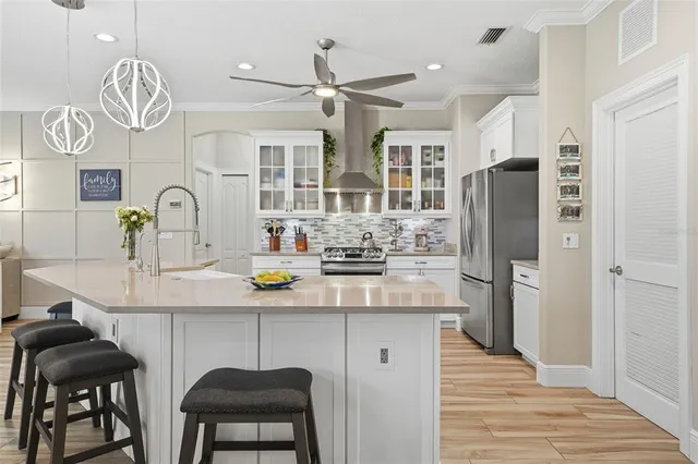 a kitchen with stainless steel appliances a dining table chairs refrigerator and cabinets