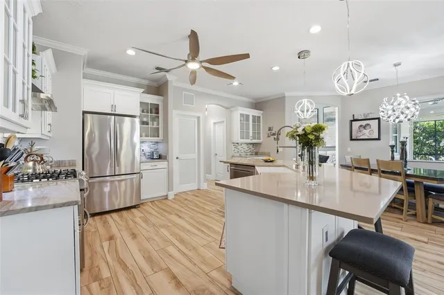 a kitchen with kitchen island a stove a refrigerator and a dining table with wooden floor