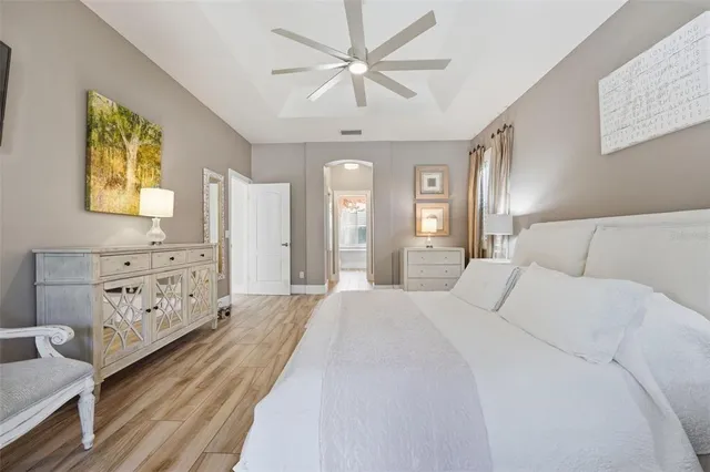 a spacious bedroom with a bed a dresser and painting on the wall