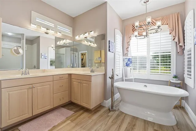 a spacious bathroom with a double vanity sink a large mirror and a bathtub
