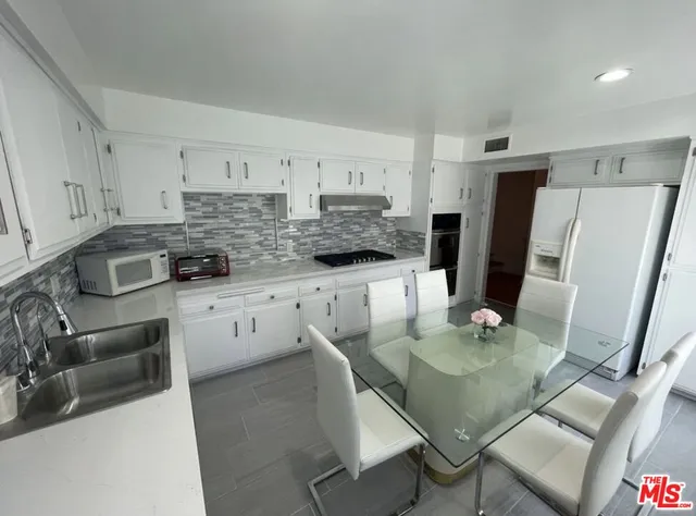 a kitchen with stainless steel appliances kitchen island granite countertop a table chairs and a refrigerator