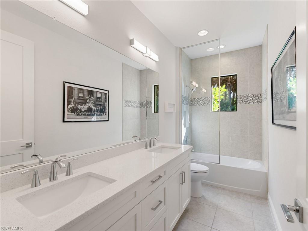 4199 11th Avenue Southwest Naples, FL 34116 - Photo 29 of 36 a bathroom with a toilet a sink a mirror and a bathtub