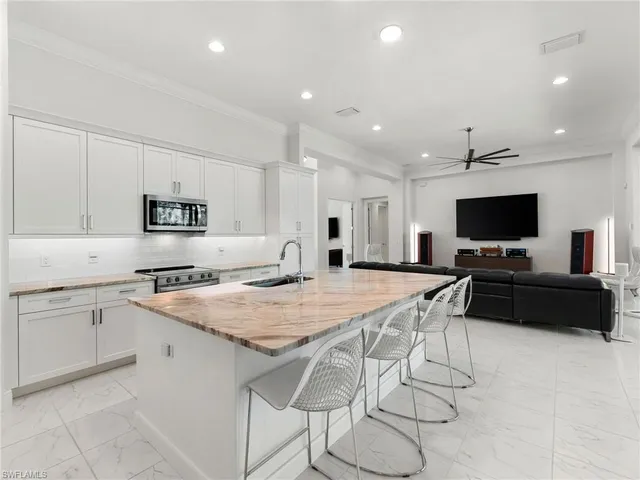 a kitchen with stainless steel appliances granite countertop a stove top oven a sink dishwasher and a refrigerator with wooden floor