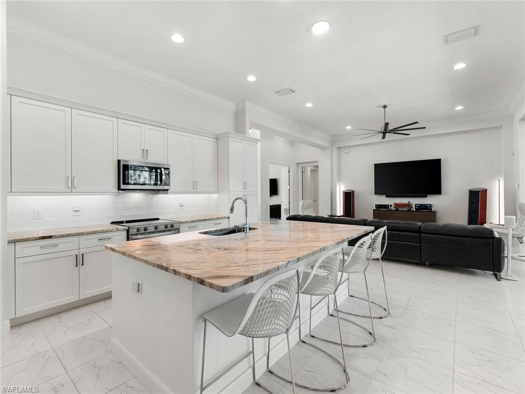4199 11th Avenue Southwest Naples, FL 34116 - Photo 5 of 36 a kitchen with stainless steel appliances granite countertop a stove top oven a sink dishwasher and a refrigerator with wooden floor