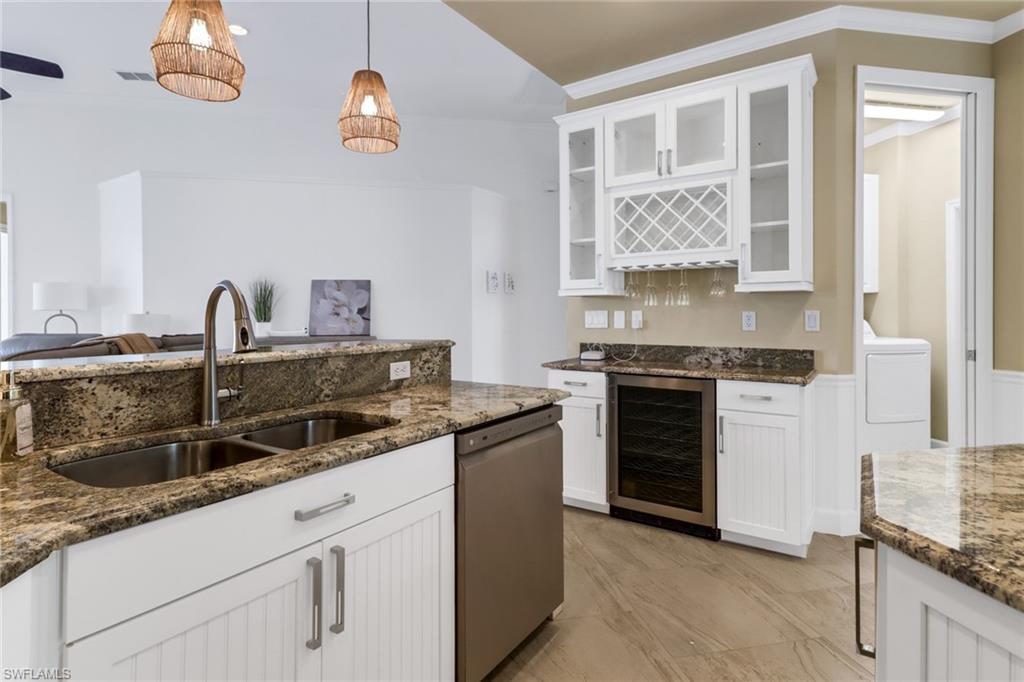 3157 Sundance Circle Naples, FL 34109 - Photo 22 of 50 Kitchen featuring hanging light fixtures, white cabinetry, sink, wine cooler, and stainless steel dishwasher
