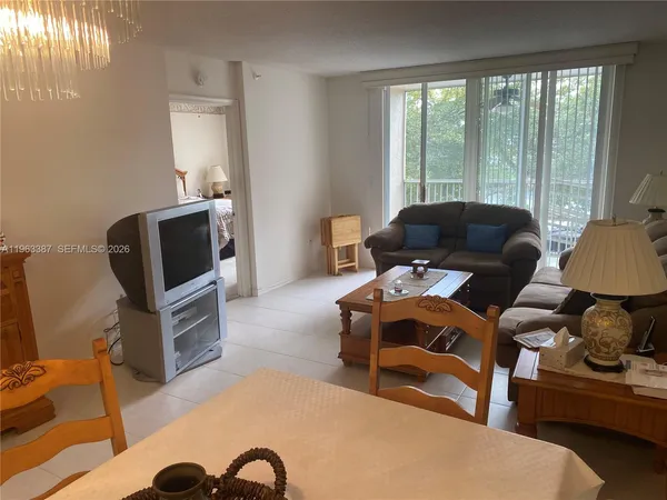 a living room with furniture a flat screen tv and a floor to ceiling window
