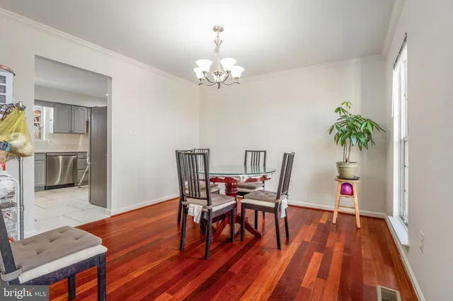 a dining room with wooden floor a chandelier a wooden table and chairs