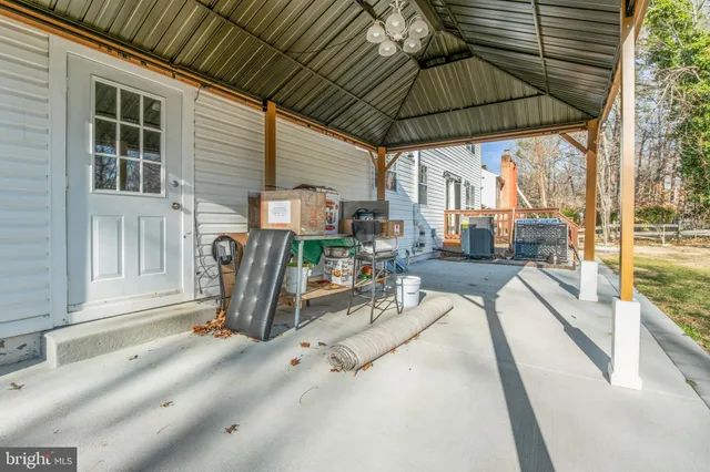 a view of a patio with table and chairs under an umbrella with a small yard