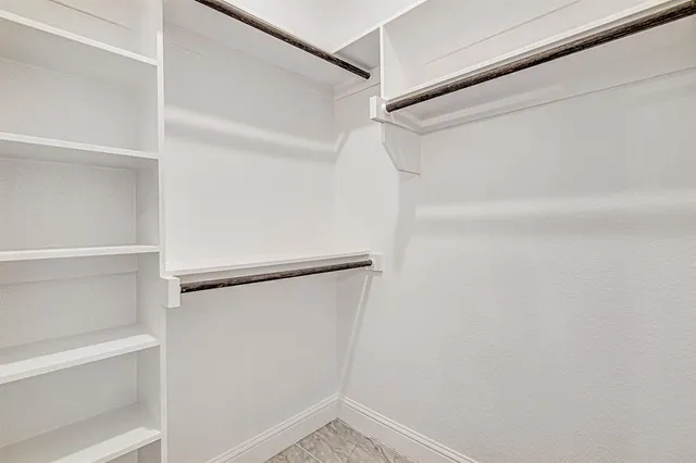 a view of walk in closet with empty racks