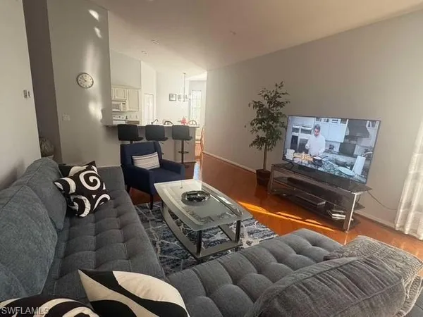 a living room with furniture a flat screen tv and kitchen view