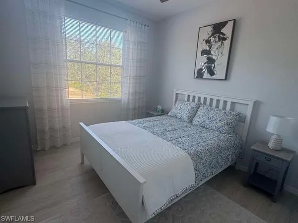 a bedroom with a bed wooden floor and window