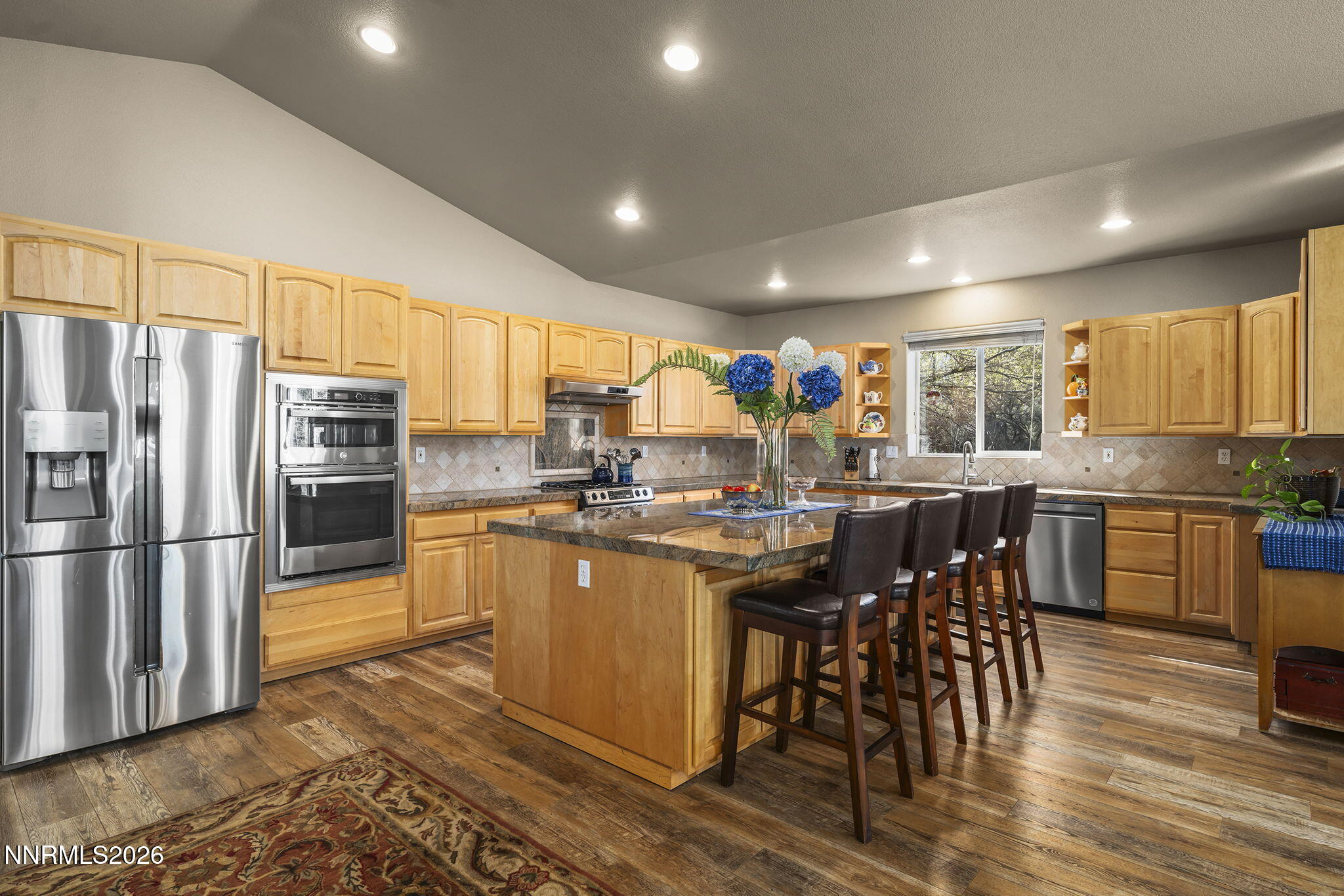 12635 Silver Wolf Road Reno, NV 89511 - Photo 21 of 48 a kitchen with stainless steel appliances kitchen island granite countertop a refrigerator a stove a sink a dining table and chairs with wooden floor