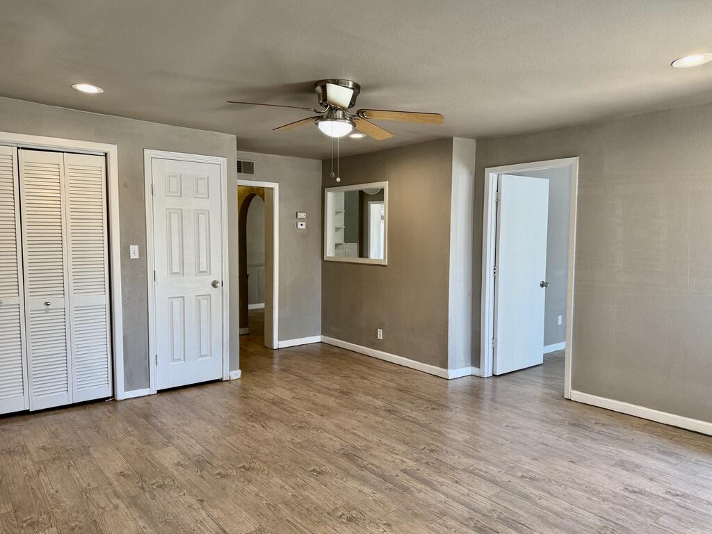 4818 36th Street Lubbock, TX 79414 - Photo 4 of 25 an empty room with wooden floor chandelier fan and windows