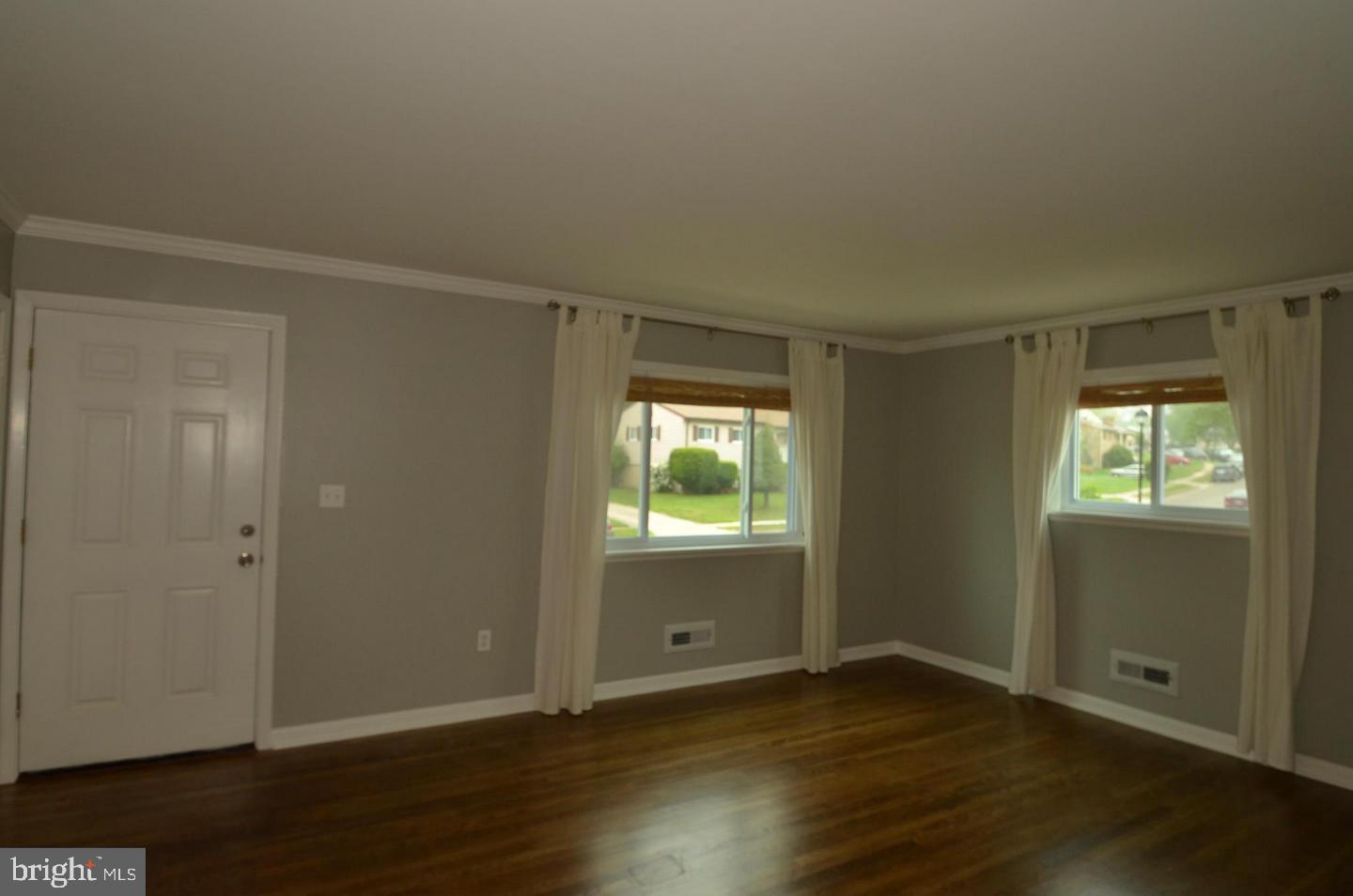 6104 Chanceford Road Baltimore, MD 21228 - Photo 3 of 17 an empty room with wooden floor cabinet and windows