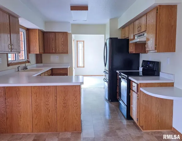 a kitchen with stainless steel appliances granite countertop a refrigerator a stove and a sink with wooden cabinets