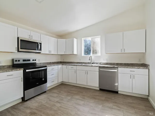 a kitchen with granite countertop cabinets stainless steel appliances and a window