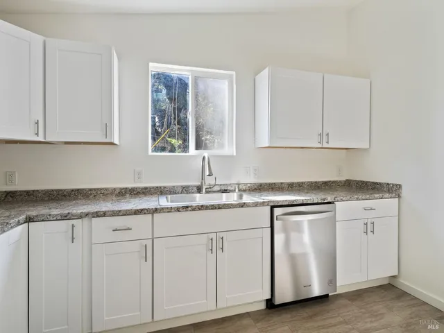 a kitchen with granite countertop white cabinets white appliances and a sink