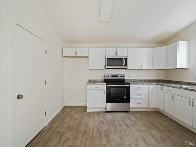 a kitchen with granite countertop white cabinets and stainless steel appliances