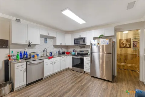 a kitchen with a refrigerator a stove a sink dishwasher and a refrigerator with wooden floor