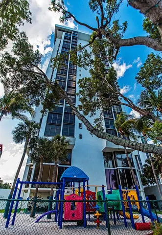 a front view of house with large trees and playing area