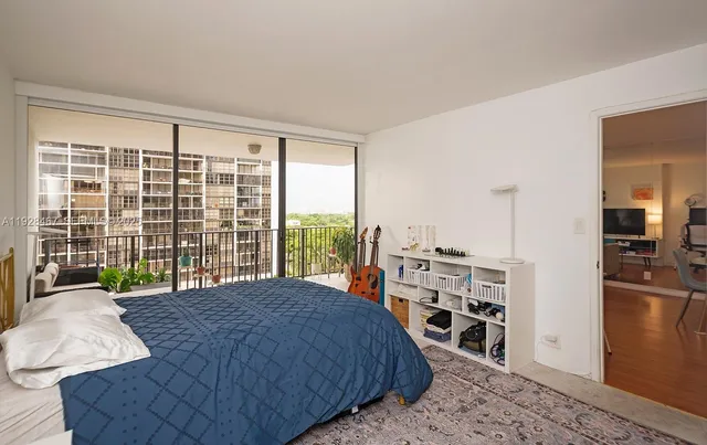 a spacious bedroom with a bed a dresser and a large window