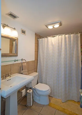 a bathroom with a sink a toilet and shower curtain