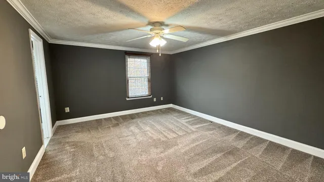 an empty room with windows and chandelier fan