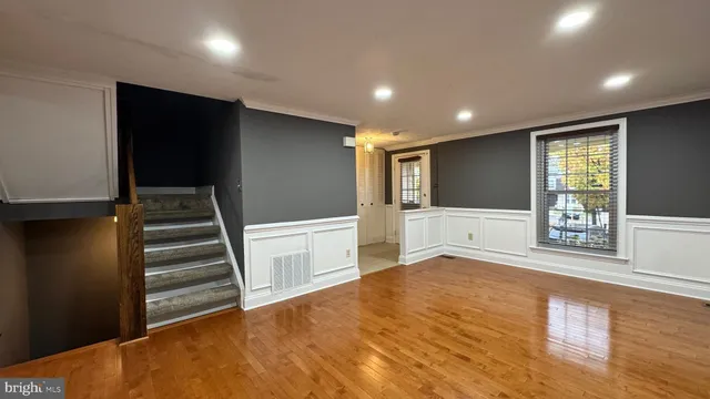 a view of an empty room with wooden floor and stairs
