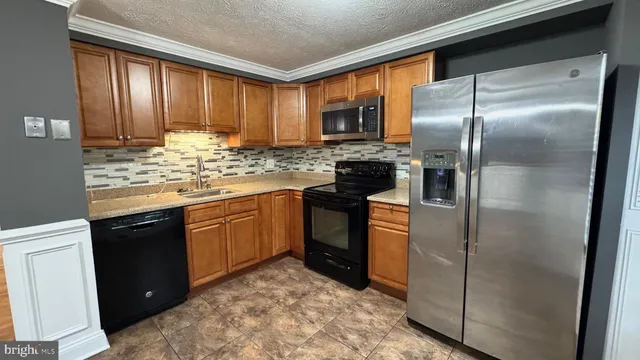 a kitchen with stainless steel appliances granite countertop a refrigerator a stove and a sink
