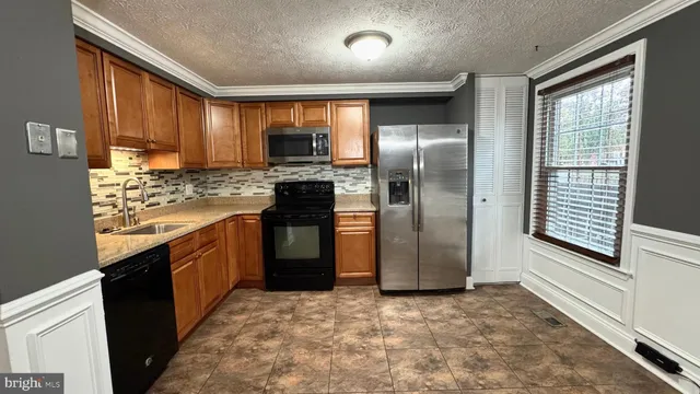 a kitchen with stainless steel appliances granite countertop a refrigerator a stove and a sink