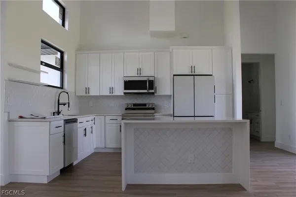 a kitchen with stainless steel appliances granite countertop a refrigerator a stove a sink and a microwave