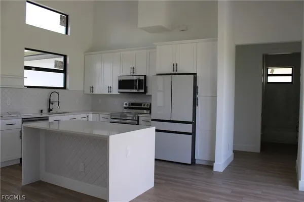 a kitchen with appliances a sink a refrigerator and cabinets